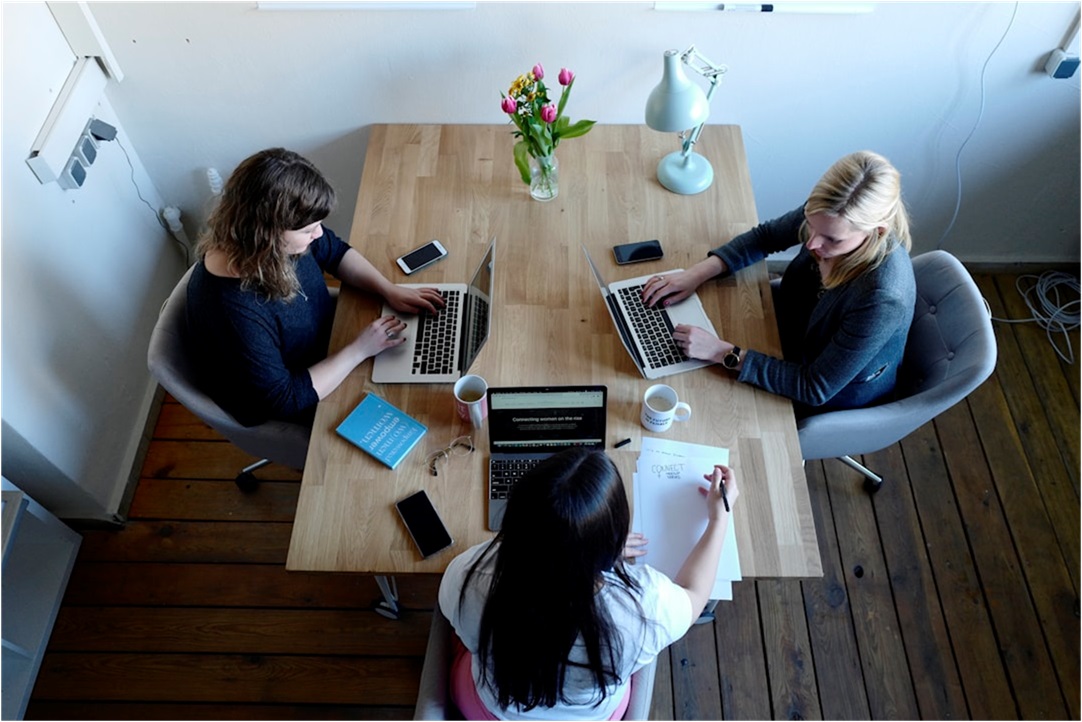 Team members gathered around a table in an office conference room, discussing how proposal management tools enhance collaboration and communication