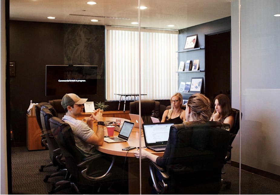 Team members gathered around a table in an office conference room, discussing how proposal management tools streamline proposal creation and save time